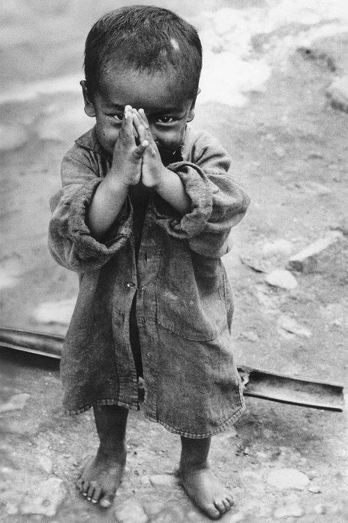 Young child with their hands together in front of their face